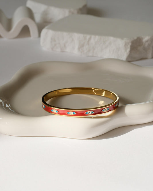 Gold and red bracelet on a textured beige surface