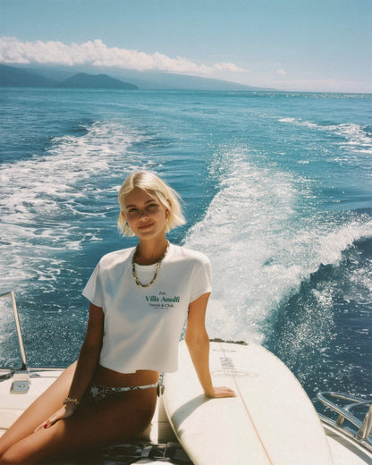 Woman sitting on a boat in the ocean with mountains in the background