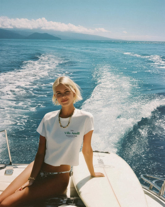Woman sitting on a boat in the ocean with mountains in the background